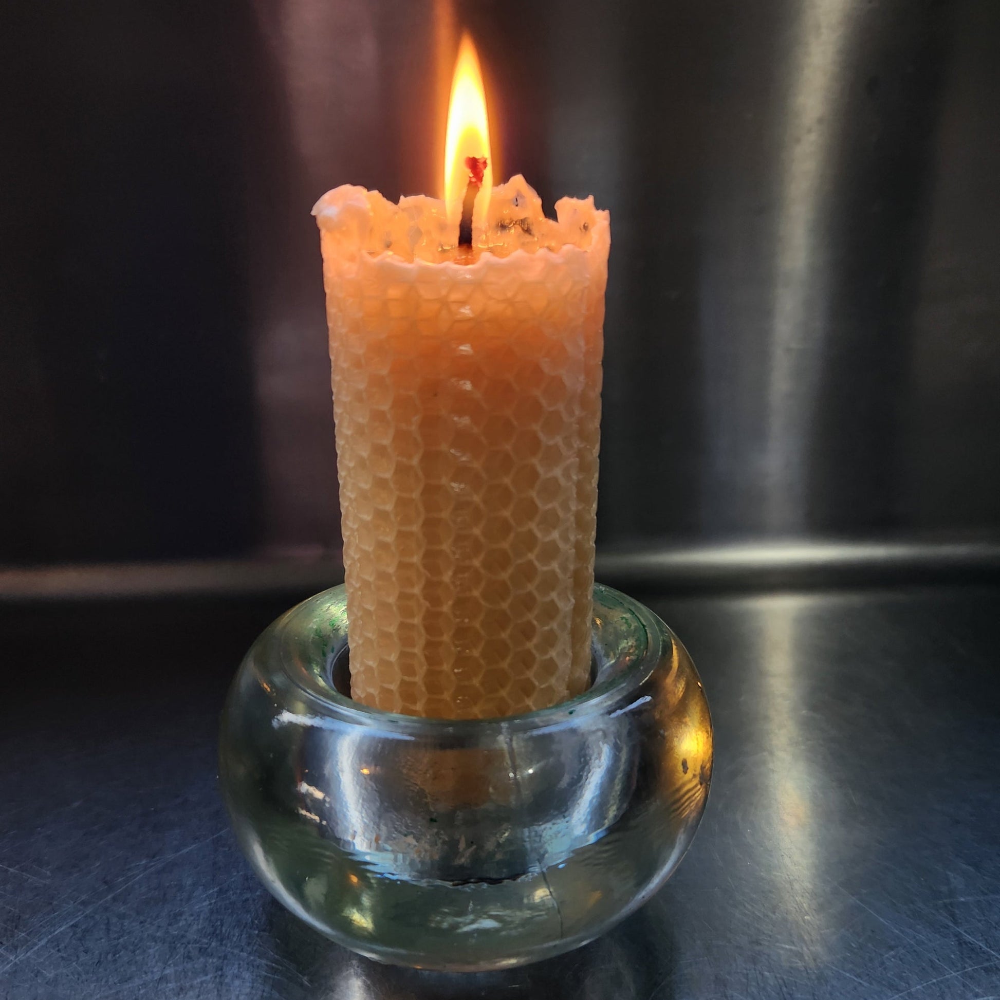Close-up of a lit candle with a glass holder against a dark background