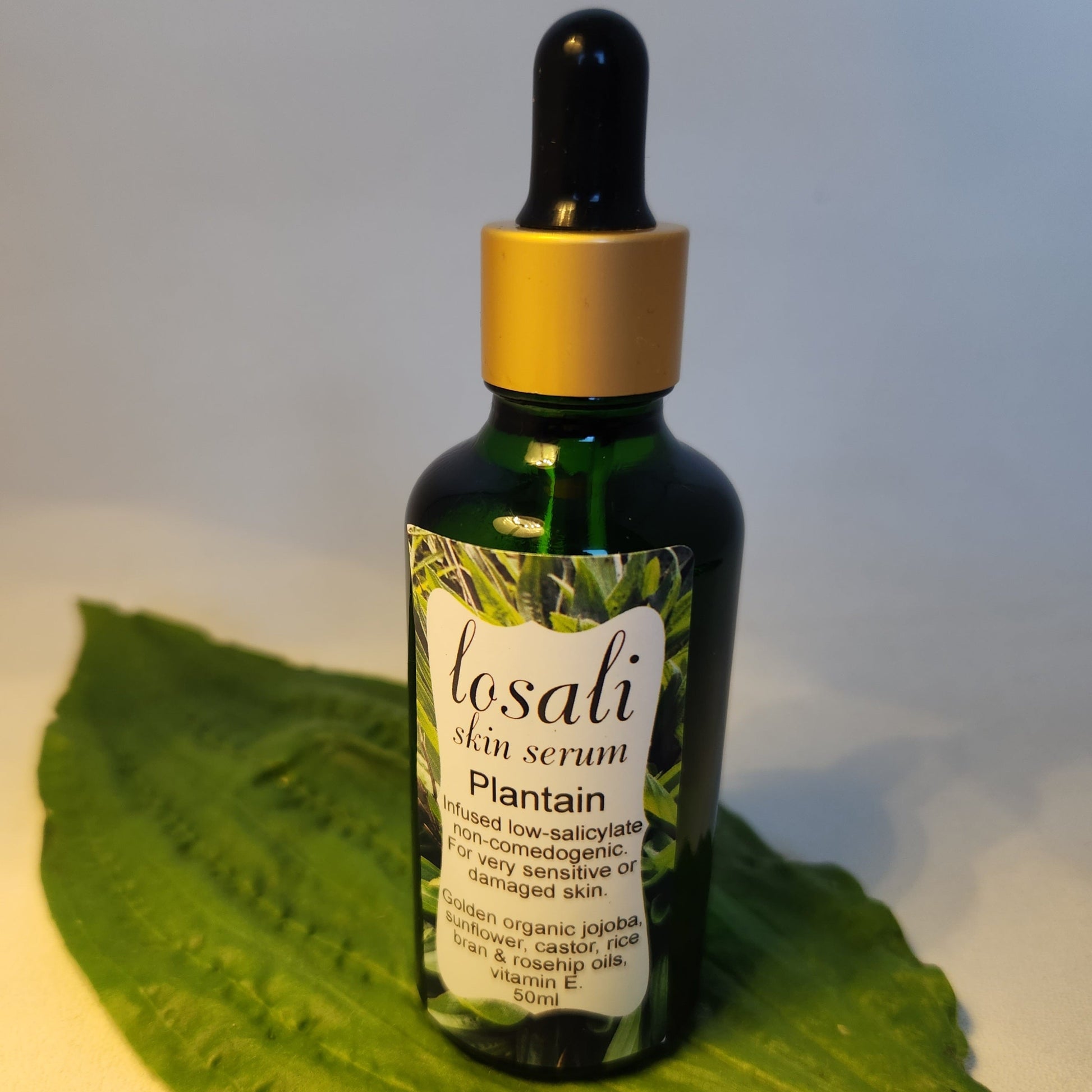 Losali skin serum bottle on a green leaf with a white background